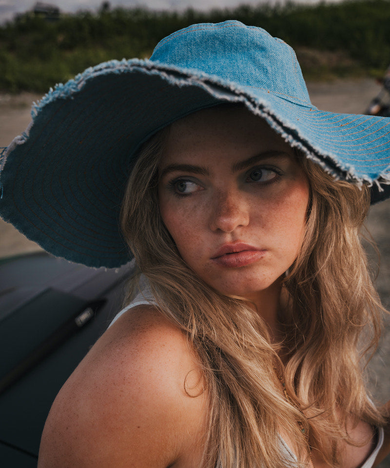 Woman wearing a blue sun hat with a blurred background wearing Soul Sister since 1969