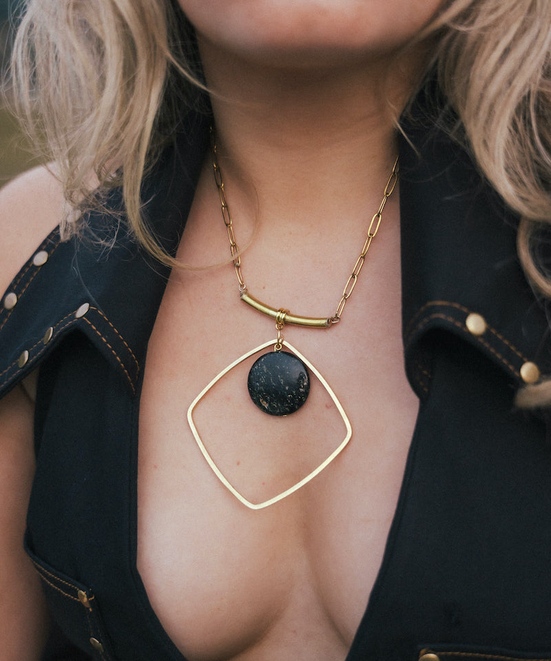 Gold necklace with a black pendant worn by a person