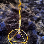 Necklace with a gold triangle pendant on a dark textured background