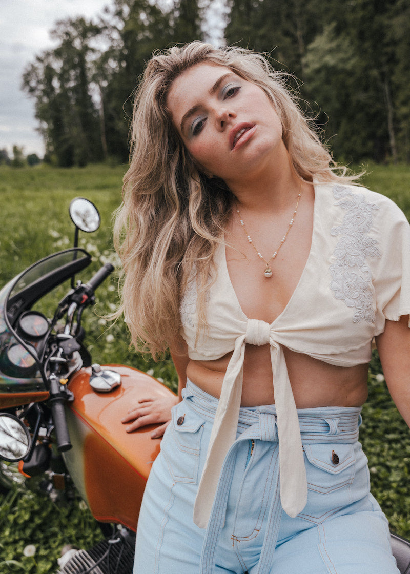 Woman standing next to a motorcycle in a grassy field Soul wearing Sister since 1969.
