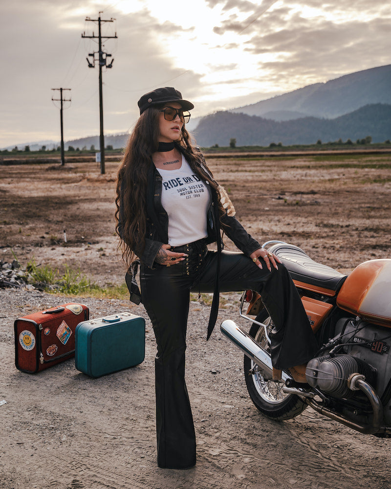 Woman in a desert setting with a motorcycle and suitcases, wearing a 'Ride or Die' t-shirt wearing Soul Sister since 1969.