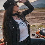 Woman with long hair and a hat standing outdoors with mountains in the background wearing Soul Sister since 1969.