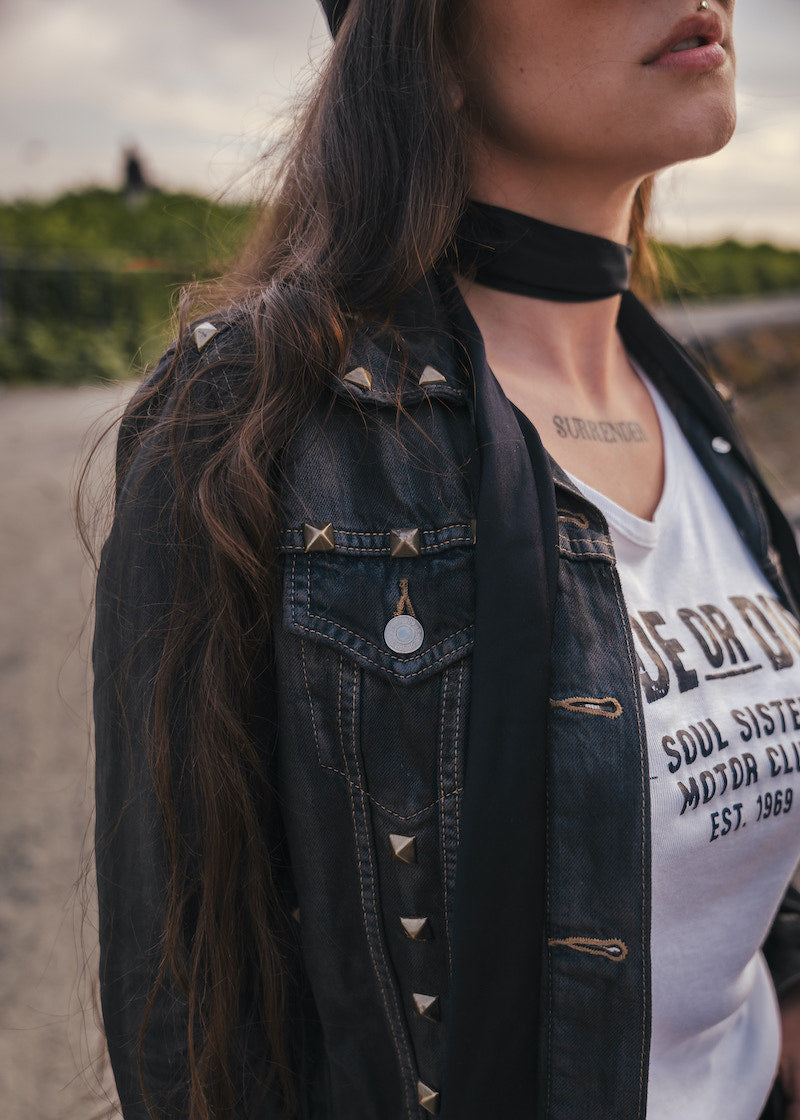 Person wearing a black denim jacket and white graphic t-shirt with text wearing Soul Sister since 1969.