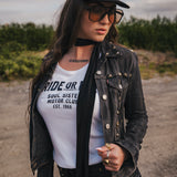 Woman wearing a black jacket, white t-shirt with text, and sunglasses outdoors. wearing Soul Sister since 1969.