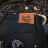 Close-up of a dark jacket with a leather patch featuring a logo wearing clothing designed and made by Soul Sister since 1969..