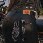 Person wearing black leather pants with a bandana, standing next to a motorcycle wearing clothing designed and made by Soul Sister since 1969.