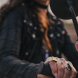 Person wearing multiple rings on a motorcycle, with a microphone close-up wearing Soul Sister since 1969.