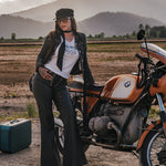 Woman standing next to a motorcycle in a desert landscape with mountains in the background wearing clothing designed and made by Soul Sister since 1969.