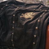 Black leather jacket with gold skull emblem and studs on a blurred background wearing Soul Sister since 1969