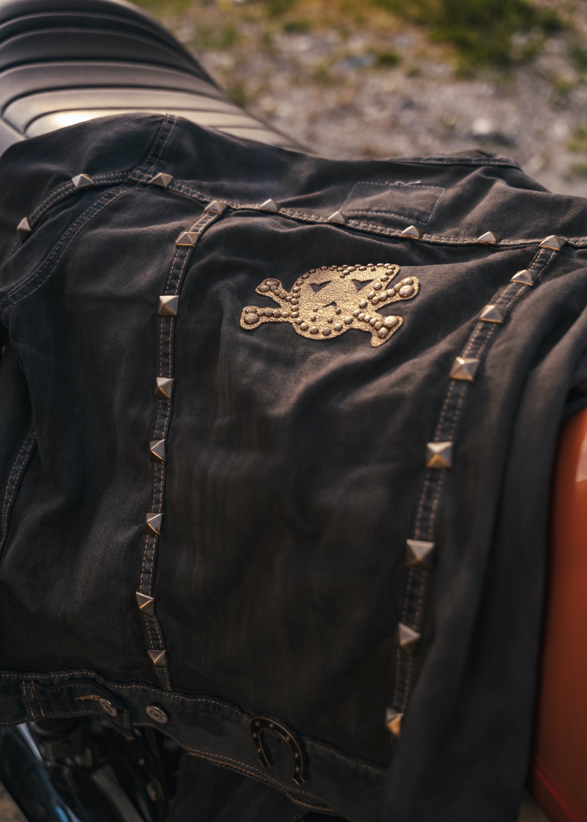 Black leather jacket with gold skull emblem and studs on a blurred background wearing Soul Sister since 1969