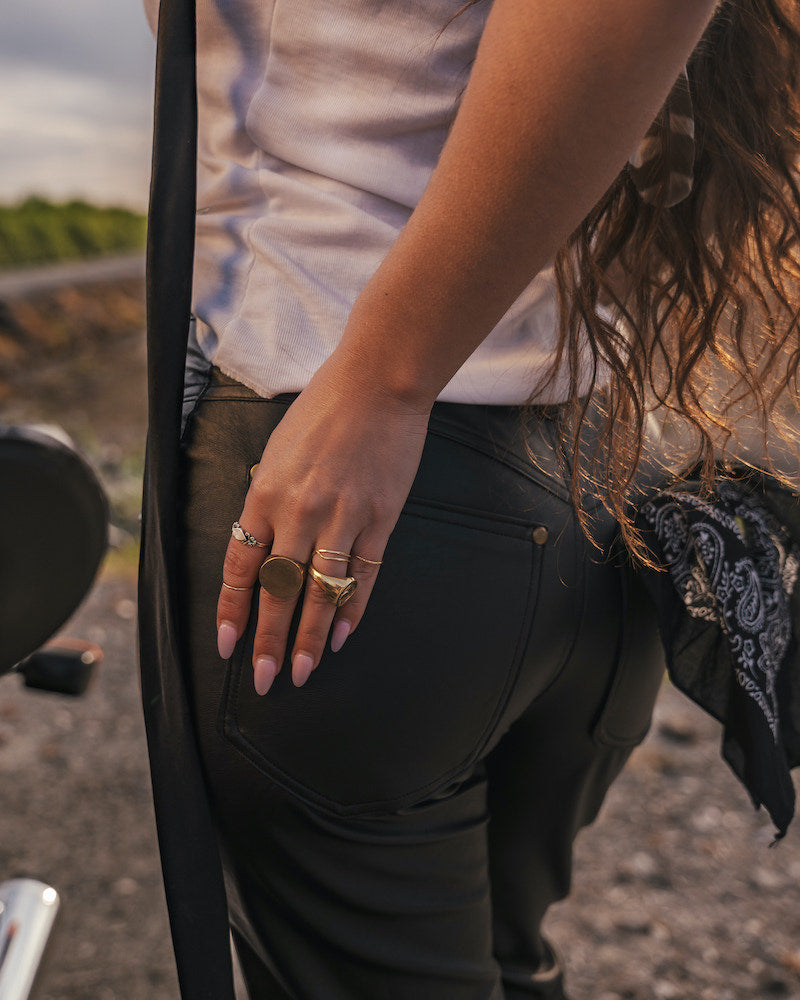 Person wearing black pants with a focus on their hand and jewelry wearing clothing designed and made by Soul Sister since 1969.