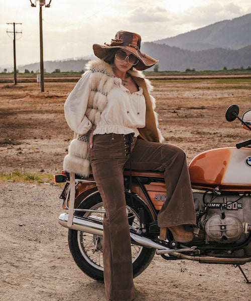 Woman in vintage attire sitting on a motorcycle in a desert landscape wearing Soul Sister since 1969