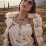 Woman wearing sunglasses and a fur vest in a desert landscape wearing soul sister since 1969