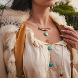 Person wearing a white blouse with turquoise beads and gold necklace, outdoors. wearing soul sister since 1969