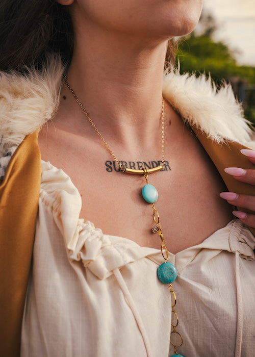 Necklace with turquoise stones and gold chain worn by a person outdoors wearing soul sister since 1969
