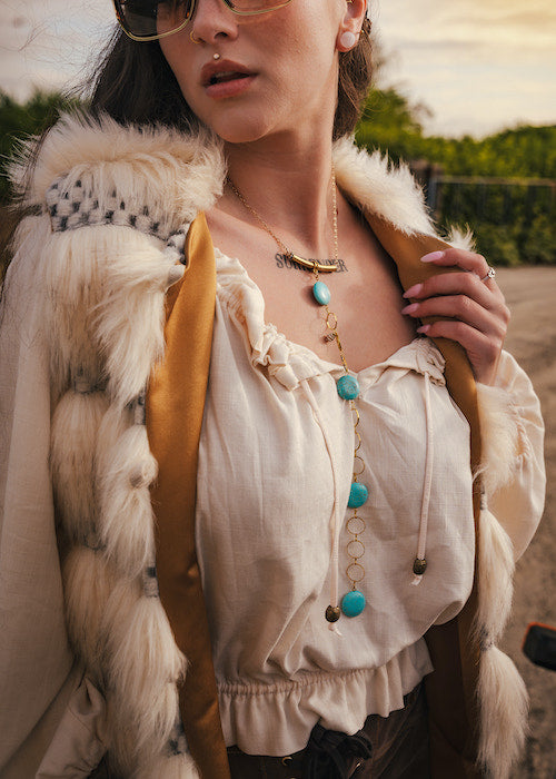 Person wearing a fur vest and white blouse with accessories outdoors wearing soul sister since 1969