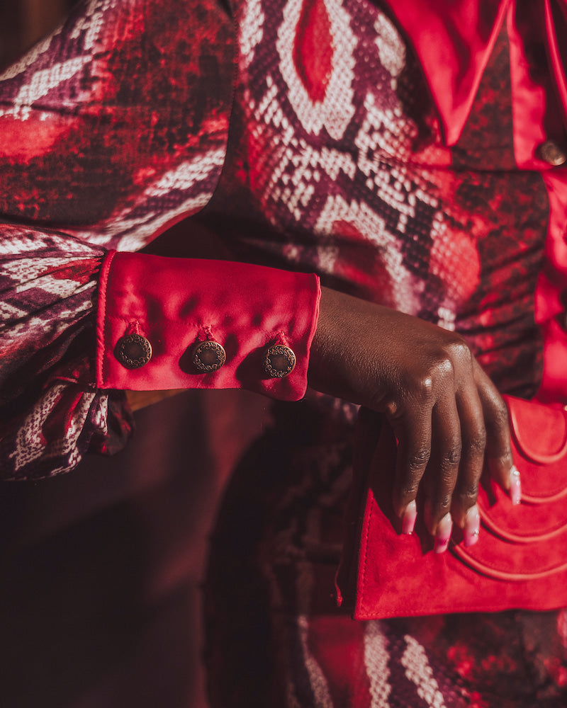Close-up of a person wearing a red and black patterned garment with a focus on the sleeve and hand.