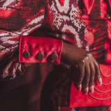 Close-up of a person wearing a red and black patterned garment with a focus on the sleeve and hand.