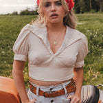 Woman wearing a white top and denim shorts with a red bandana in a grassy field wearing Soul Sister since 1969.