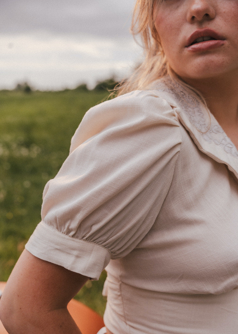 Woman wearing a beige blouse with puffed sleeves in a natural setting wearing Soul Sister since 1969