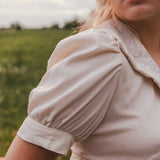 Woman wearing a beige blouse with puffed sleeves in a natural setting wearing Soul Sister since 1969