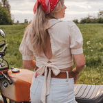 Woman with a red bandana standing next to a motorcycle in a field wearing Soul Sister since 1969