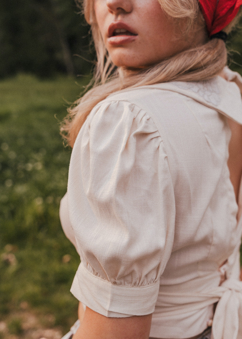 Woman wearing a beige blouse with puffed sleeves in a natural setting wearing Soul Sister since 1969